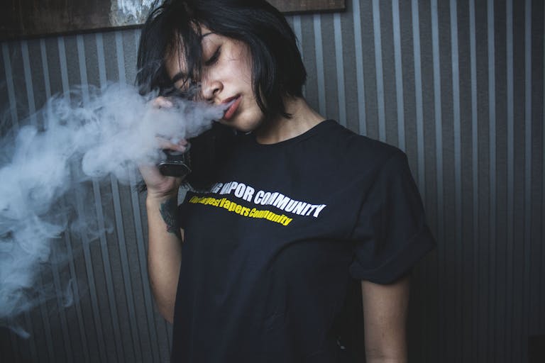 A young woman with a calm expression vapes indoors, creating a tranquil and modern atmosphere.